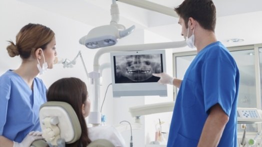 Dentist and dental team member showing a patient x rays of their teeth