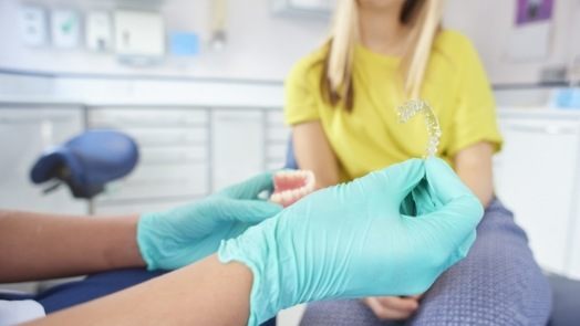 Dentist holding Invisalign tray while talking to patient