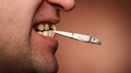 Close up of man holding cigarette between his teeth
