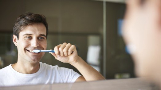 Smiling man brushing his teeth
