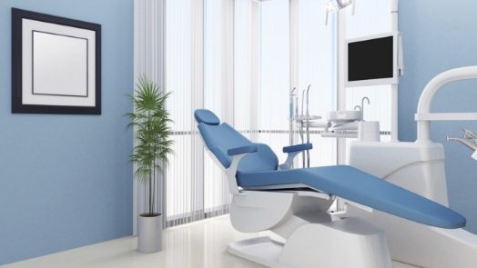 Light blue dental chair in exam room with light blue walls