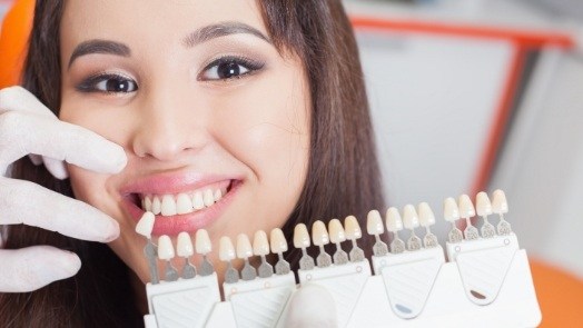 Young woman smiling next to dental veneers while visiting cosmetic dentist in Tulsa