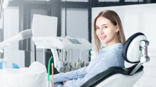 Young woman turning back in dental chair to smile at the camera