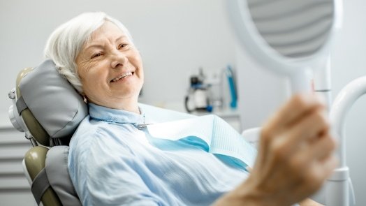 Senior dental patient admiring her smile in mirror