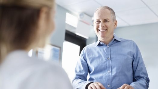 Man talking to dental team member at front desk