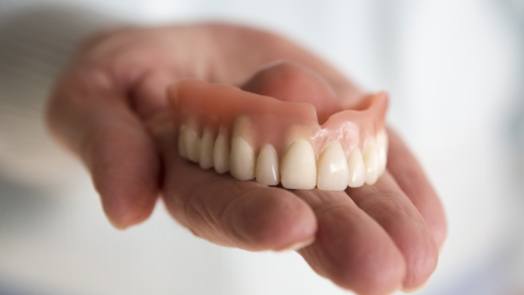 Person holding a full denture in Tulsa in their hand