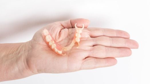 Person holding a partial denture in their hand