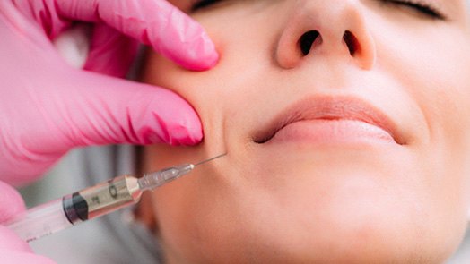 Woman having filler injected into her cheek
