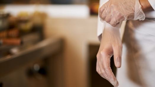 Person in white lab coat pulling on a clear glove