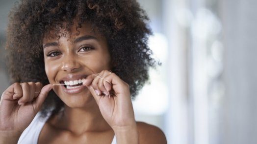 Woman smiling while flossing her teeth