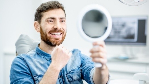 Dental patient admiring his smile in mirror