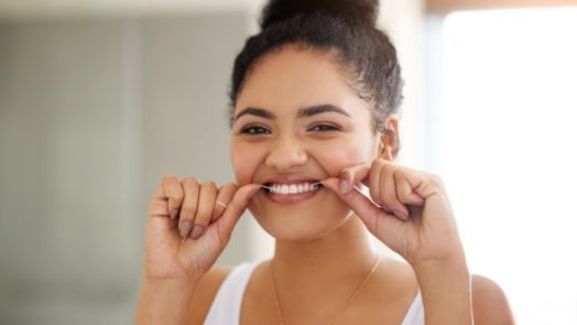 Woman smiling while flossing her teeth