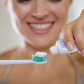 Person putting toothpaste on electric toothbrush