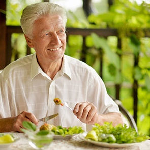 A handsome senior man eating a healthy breakfast outdoors