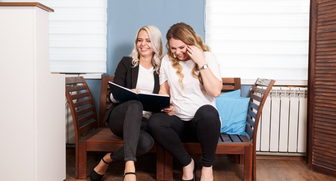 Two women laughing on bench in Tulsa dental office