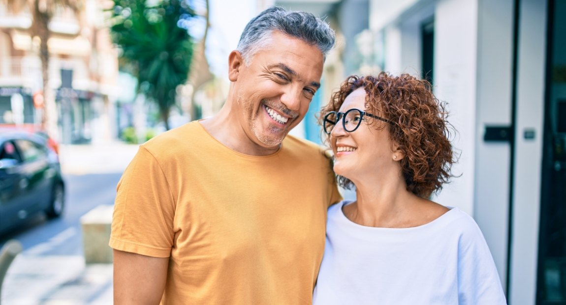 Smiling man and woman standing on city sidewalk