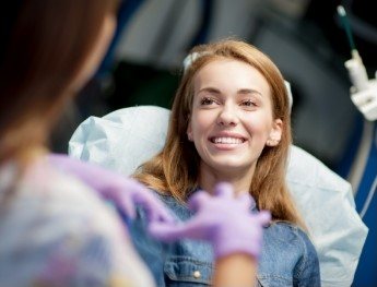patient smilng up at team member in dental chair in Tulsa
