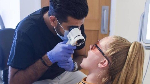 Dentist performing oral cancer screening with Velscope device