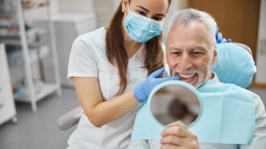 Senior dental patient admiring his smile in mirror