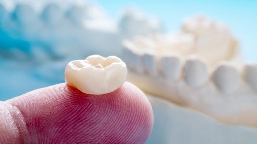 Close up of person holding dental crown on their finger