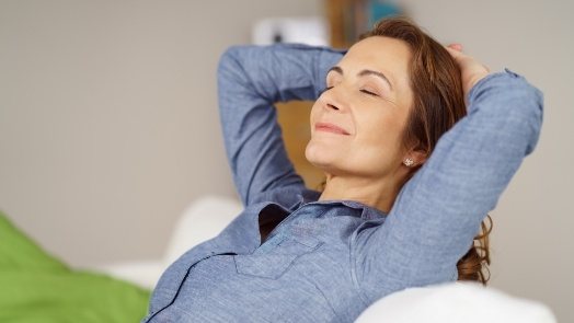 Smiling woman relaxing with eyes closed and her hands behind her head