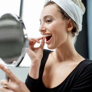 Woman placing take home teeth whitening trays in her mouth