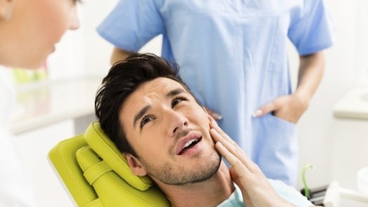 Dental patient holding his cheek in pain before T M J treatment in Tulsa