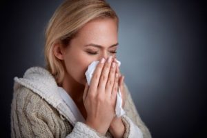 A woman with a cold blowing her nose