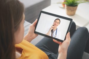 woman in yellow shirt attending telemedicine appointment on her tablet