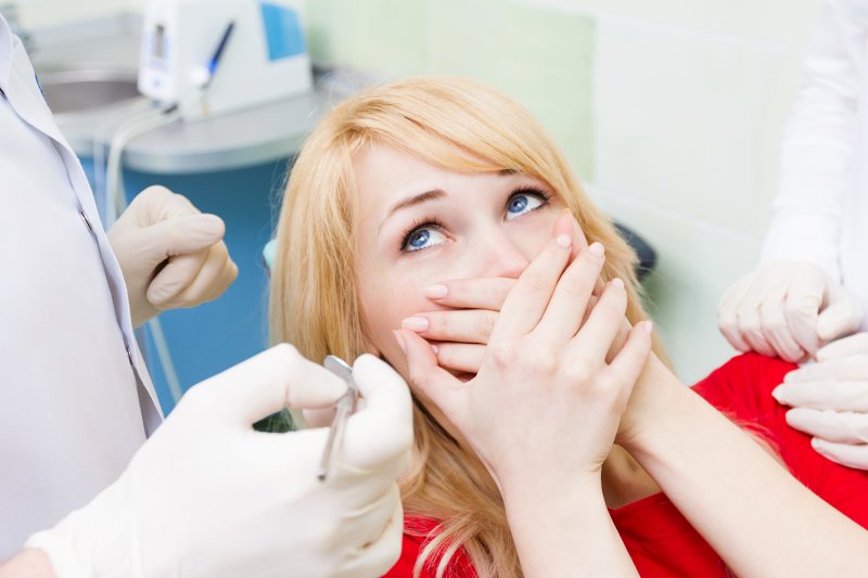 a young woman holding her hands over her mouth out of embarrassment at the dentist’s office 