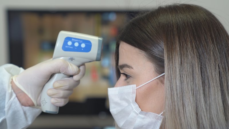 Masked woman having her temperature taken