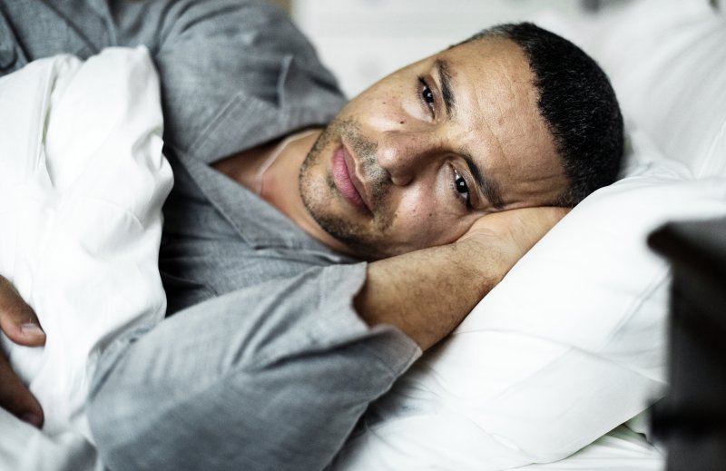 Anxious man with sleep apnea lying awake in bed
