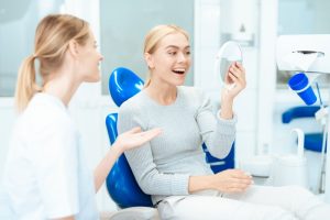 a woman with her dentist and smiling at her cosmetic treatment