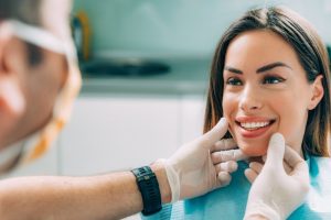 a woman smiling happily at her dentist after her cosmetic treatment