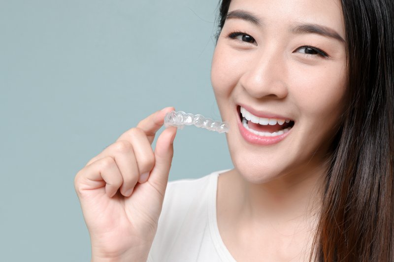 patient holding Invisalign tray and smiling 