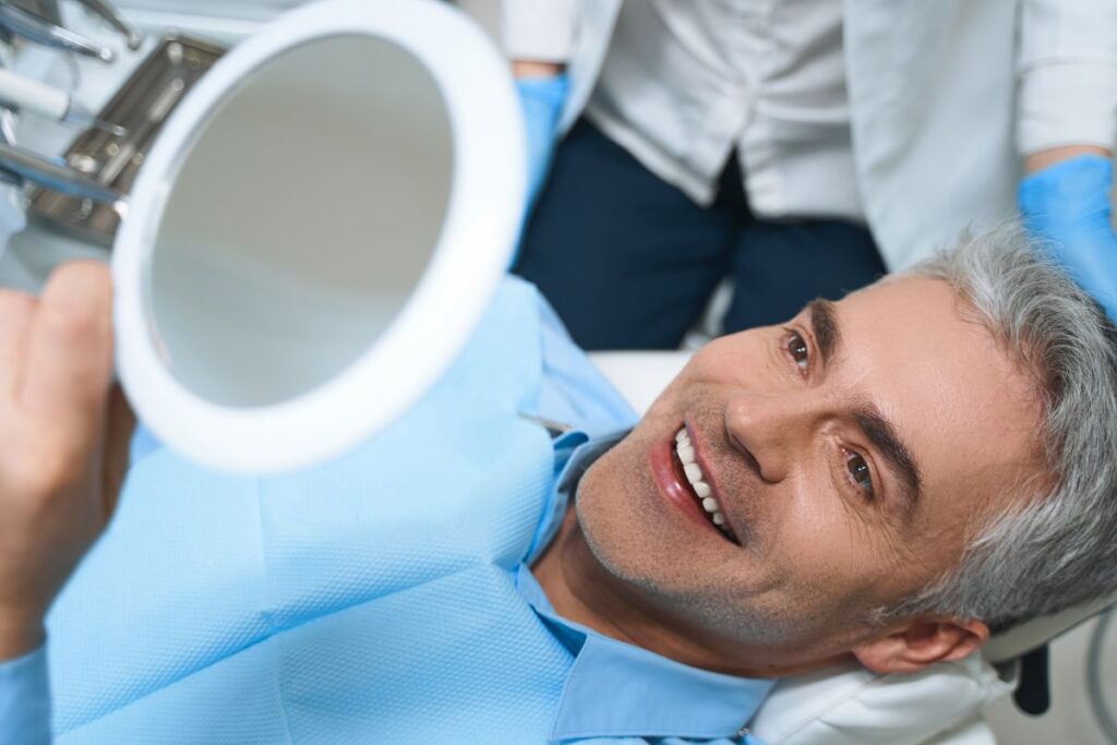A man looking at his smile in the mirror